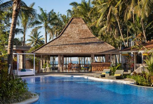 a resort swimming pool with a gazebo and palm trees at Saba Villa by Sanga Sanga Hospitality in Saba