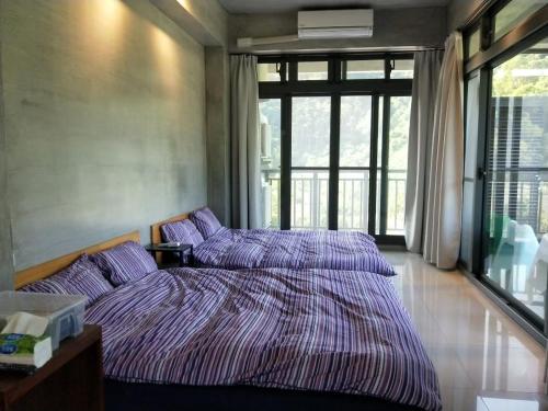 two beds in a bedroom with a large window at Sun Moon Mountain Farm Homestay in Yuanshan