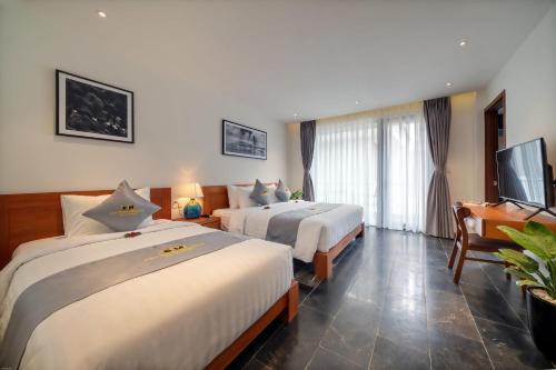 a hotel room with two beds and a flat screen tv at Em's House Hoi An Homestay in Hoi An