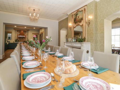 a long wooden table with plates and wine glasses at Milton Manor in Gillingham