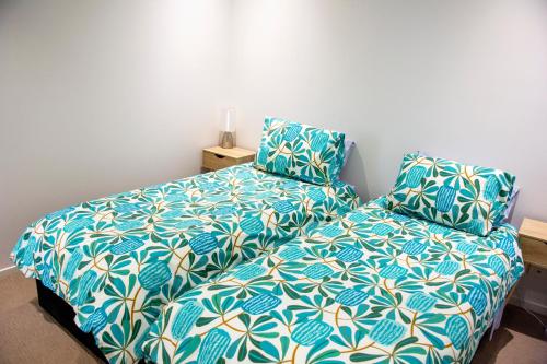 a bedroom with a bed with a blue and white comforter at Absolute Waterfront - Tropical Sunrise Apartment Over The Water in Darwin