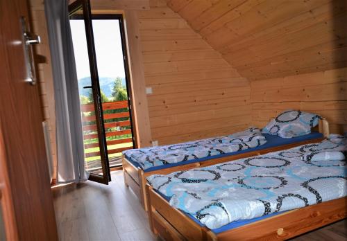 a bedroom with two beds and a balcony at DOMY POD WIERZBĄ - KASINA WIELKA in Kasina Wielka