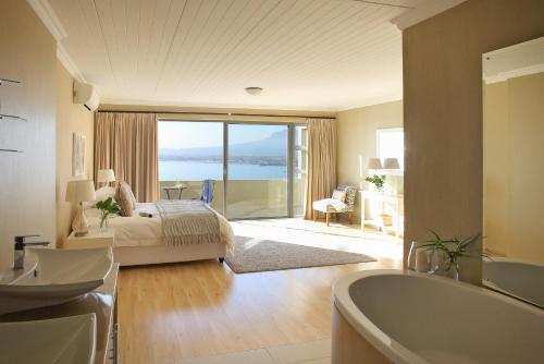 a bedroom with a bed and a bath tub and a bathroom at Bayview in Gordonʼs Bay