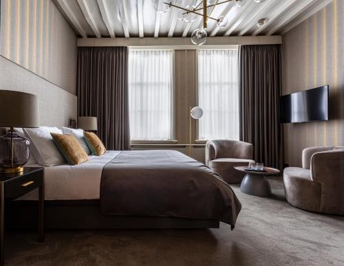 a bedroom with a large bed and two chairs at Poorter Boutique Hotel Brielle in Brielle