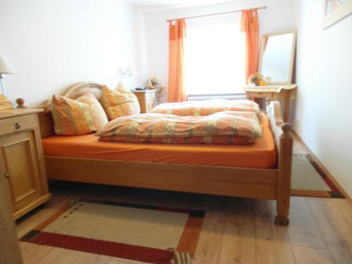 a bedroom with a bed with an orange comforter and a window at Haus Edelweiss Jungholz in Jungholz