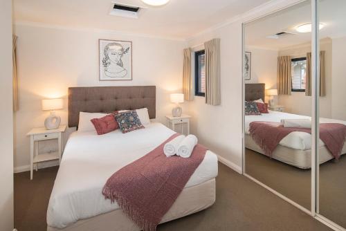 a bedroom with two beds and a mirror at Apartment 36 in Margaret River Town