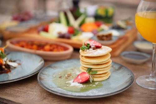 a table with plates of pancakes and a glass of orange juice at Duven Hotel Cappadocia in Uchisar
