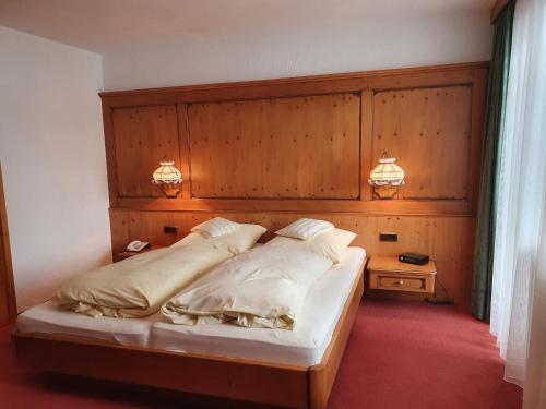 a bedroom with a bed with a wooden headboard at HOTEL WALDHORN in Jungholz