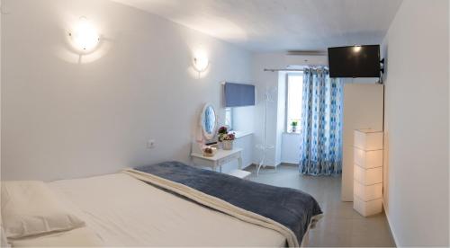 a white bedroom with a bed and a television at Sokaki House in Hydra