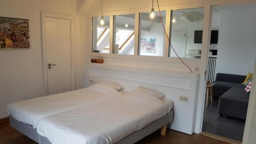 a bedroom with a white bed and a window at Le Chanteclair in Gembloux