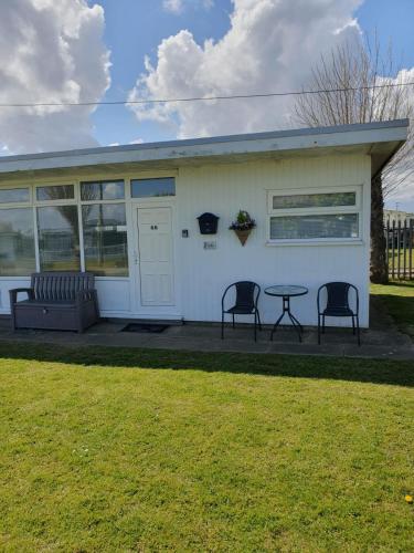 uma casa branca com duas cadeiras e uma mesa em Chalet 66 em Skegness