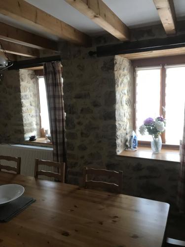 uma sala de jantar com uma mesa de madeira e 2 janelas em Maison Tranquille em Champniers-et-Reilhac