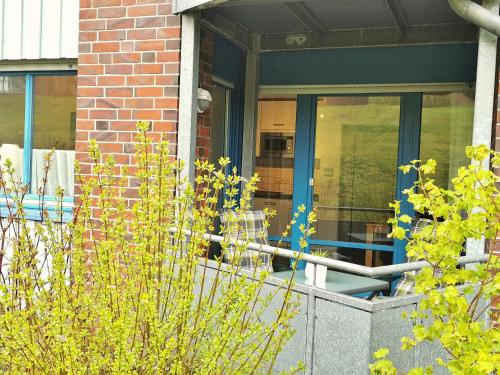 a house with a blue door and some plants at Strandkorb in Horumersiel