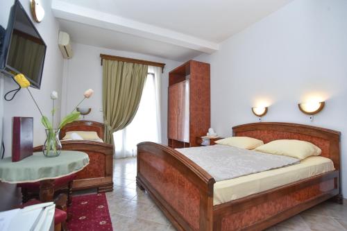 a bedroom with a bed and a television and a table at Hotel Grbalj in Budva