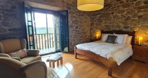 a bedroom with a bed and a stone wall at Casa Grande de Cristosende in Cristosende