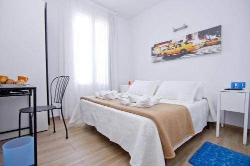 a white bedroom with a bed and a chair at Barcelona City Hotel in Barcelona