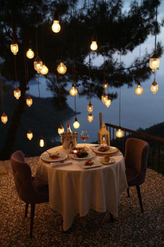 a table with plates of food on it with lights at Lissiya Hotel in Faralya