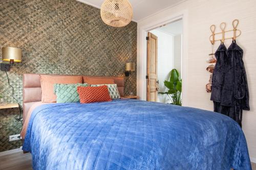 een slaapkamer met een bed met een blauw dekbed bij Beach Break Deco & Sleeping in Katwijk aan Zee