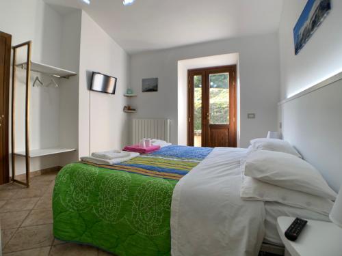 a bedroom with a large bed with a green blanket at La Fattoria dei Sibillini in Montemonaco