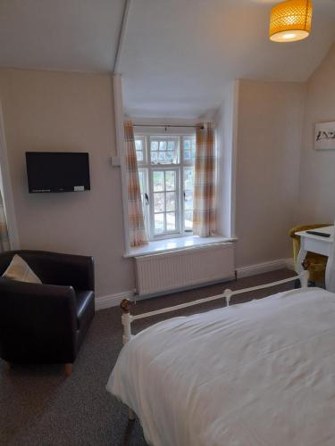 a bedroom with a bed and a chair and a window at The Raven Inn in Ruthin