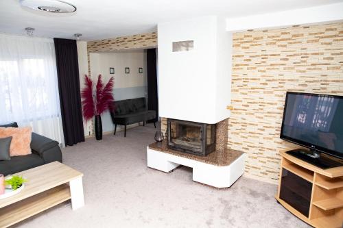 a living room with a fireplace and a television at Žvejo kiemelis in Šilutė
