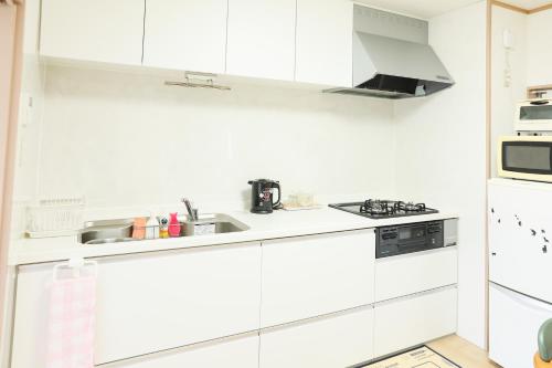 a white kitchen with a sink and a microwave at HAT Kujo, near from Kintetsu Kujo station 近鉄九条駅前の民泊 in Kōriyama