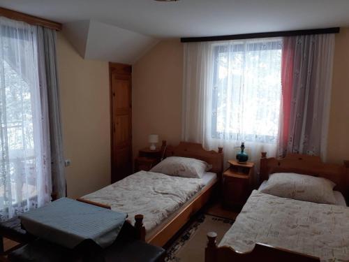 1 dormitorio con 2 camas y 2 ventanas en Smještaj na selu Porodica Gvozdenac, en Šipovo