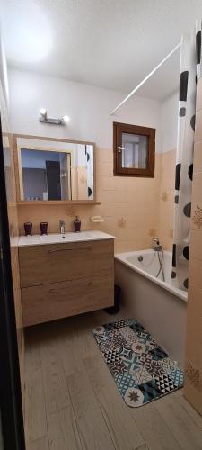 une salle de bain avec une baignoire, un lavabo et un miroir dans l'établissement Joli T2 avec jardin plage Richelieu - 6 personnes, au Cap d'Agde