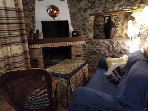 een woonkamer met een bank en een open haard bij Casa Fuensanta balcón al mar de la Alpujarra in Granada