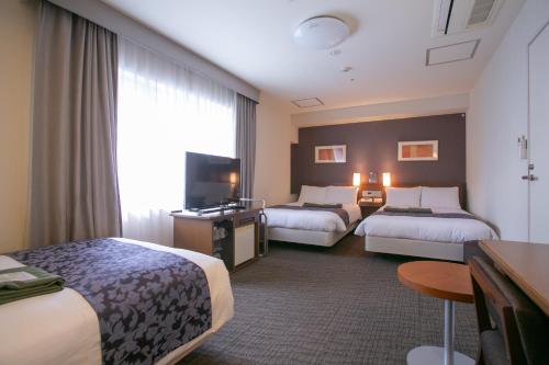 大阪市にあるホテル法華クラブ大阪のベッド2台とテレビが備わるホテルルームです。