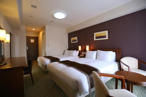 a hotel room with two beds and a table and chairs at Hotel Hokke Club Osaka in Osaka