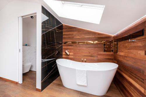 a bathroom with a white tub and wooden walls at Lapwing Residence Sopot in Sopot