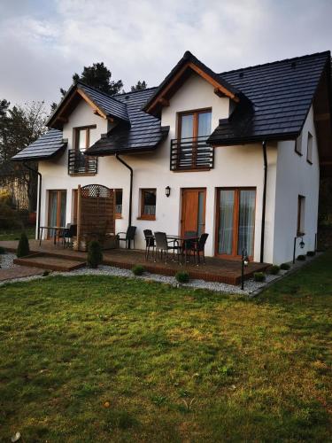 a white house with a black roof at 4 Pory Roku Apartamenty Domki Pokoje in Nadole