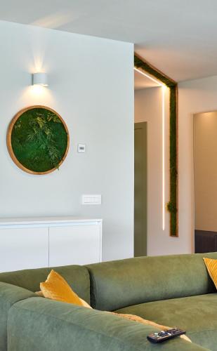 a green couch in a living room with a clock on the wall at Villa Green Forest with wellness and heated salty pool in Hum