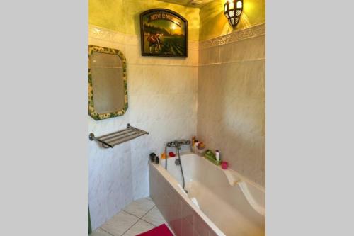 une salle de bain avec une baignoire, un lavabo et un miroir dans l'établissement Belle maison néo-bretonne à 5 minutes de la mer, à Tréveneuc