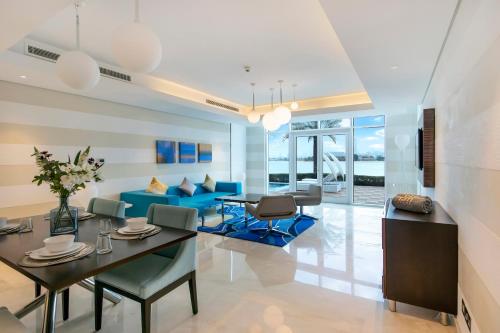 a living room with a blue couch and a table and chairs at FAM Living - Sarai Beachfront Villas - 2 in Dubai
