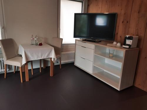 un salon avec une télévision sur une commode et une table dans l'établissement Zyba-Hotelzimmer-Vermietung Aesch Kanton Luzern, à Aesch