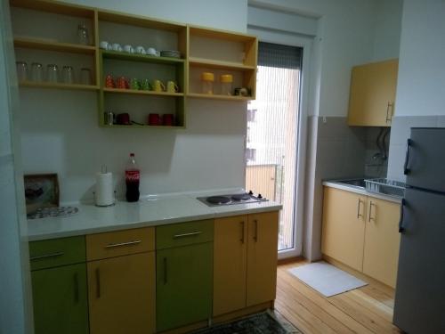 a kitchen with yellow and green cabinets and a refrigerator at Apartman Tina Sokobanja in Soko Banja