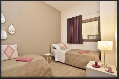 a small bedroom with two beds and a window at Mediterraneo Apartments ORO in Marzamemi