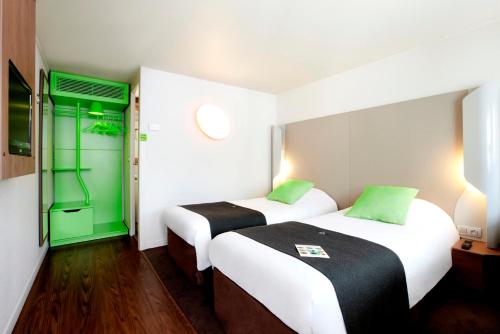 two beds in a room with a green door at Campanile Aix-en-Provence Sud - Pont de l'Arc in Aix-en-Provence