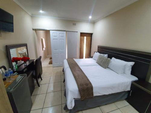 a bedroom with a bed and a desk with a mirror at SM Africa Guest House in Alberton