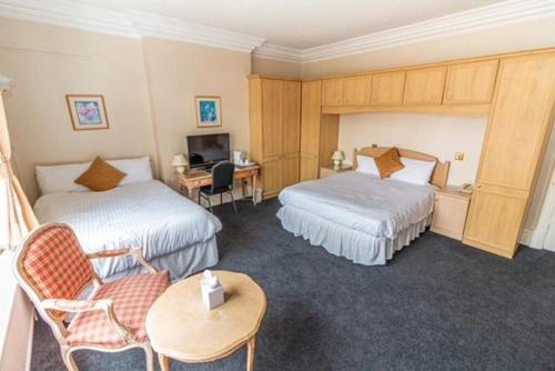 a hotel room with two beds and a desk at The Quorn Lodge Hotel in Melton Mowbray