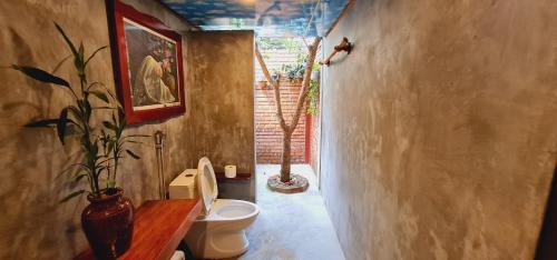 a bathroom with a toilet and a potted plant at Vu's Homestay in Phong Nha