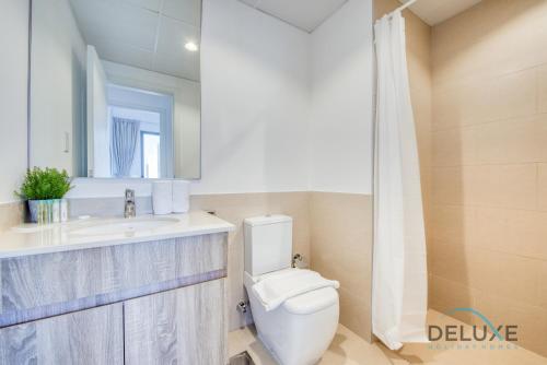 a bathroom with a toilet and a sink and a mirror at Chic 1BR in Town Square UNA Dubailand by Deluxe Holiday Homes in Dubai