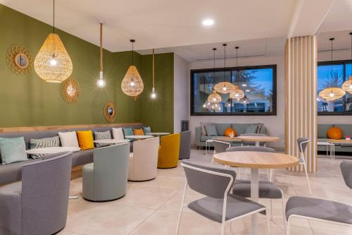 a restaurant with couches and tables and chairs at Lagrange Apart'Hôtel Antibes Olympie in Antibes
