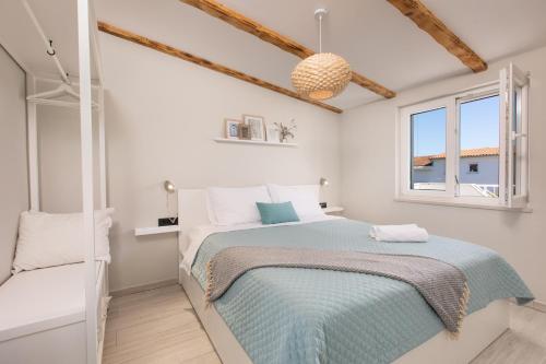 a white bedroom with a bed and a window at Villa Liva in Vantačići