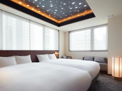 a hotel room with two beds and a large window at Agora Tokyo Ginza in Tokyo