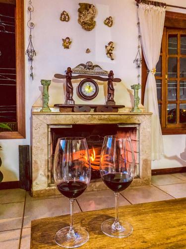 two wine glasses sitting on a table in front of a fireplace at Pousada Quintal da Lua in Capitólio