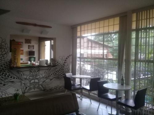- un salon avec des tables, des chaises et des fenêtres dans l'établissement Hangar Rio Hostel, à Rio de Janeiro