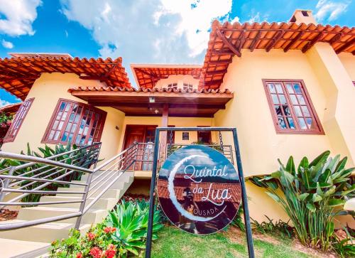 a house with a sign in front of it at Pousada Quintal da Lua in Capitólio